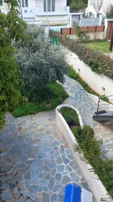 a garden with a stone walkway in a yard at Pavlos apartment in Leondárion
