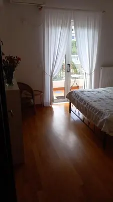 a bedroom with a bed with white curtains and a wooden floor at Pavlos apartment in Leondárion