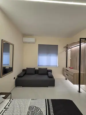 a living room with a black bed and a screen at 3siblings A2 in Athens