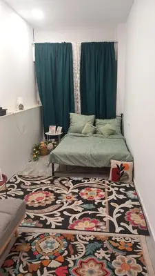 a bedroom with a bed with a rug and blue curtains at House Marios airport 3 in Spáta