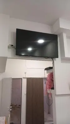 a flat screen tv hanging from the ceiling of a room at House Marios airport 3 in Spáta