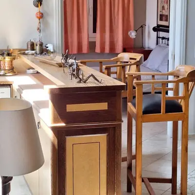 a kitchen with a counter with a sink and chairs at Villa Pepy in Áyios Konstandínos
