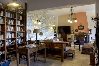 a living room with a desk and a stone wall at Villa Pepy in Áyios Konstandínos
