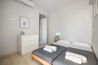 a white bedroom with a bed with towels on it at South Blue Beach & Park Apartment in Vouliagmeni in Athens