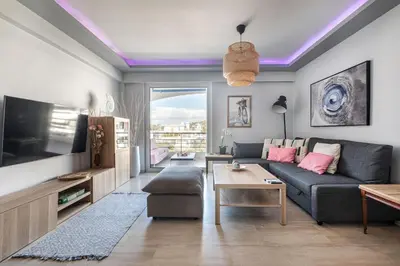 a living room with a couch and a tv at South Blue Beach & Park Apartment in Vouliagmeni in Athens