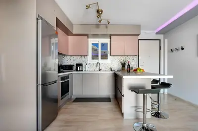 a kitchen with white appliances and pink cabinets at South Blue Beach & Park Apartment in Vouliagmeni in Athens