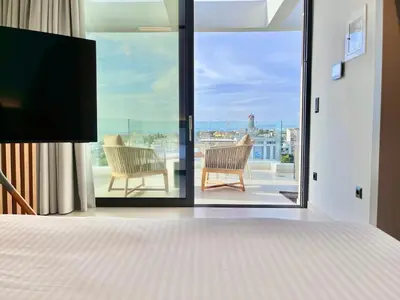 a bedroom with a bed and two chairs on a balcony at 2BR Sea View Loft with private Jacuzzi in Riviera in Athens