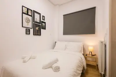 a bedroom with a white bed with a flat screen tv at Vote Athens Apartment in Athens