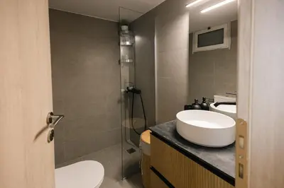 a bathroom with a sink and a toilet and a mirror at Vote Athens Apartment in Athens