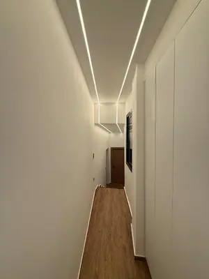 a hallway with white walls and a wooden floor at City Center Jacuzzi Lux 2master BD apartment in Athens