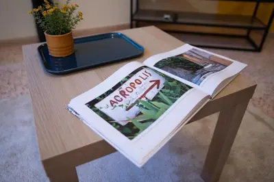 a wooden table with a magazine on top of it at 2 KING beds, 81 sqm, Downtown near Metro in Athens