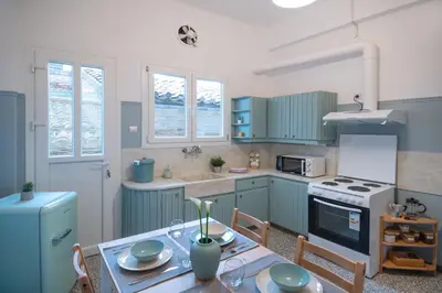 a kitchen with blue cabinets and a table with a dining room at 2 KING beds, 81 sqm, Downtown near Metro in Athens