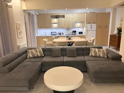 a living room with a couch and tables and a kitchen at Pireaus Center Apartment in Piraeus
