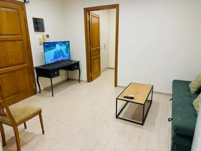 a living room with a couch and a table with a television at Brown Port 2 bedroom 2wc flat in Piraeus