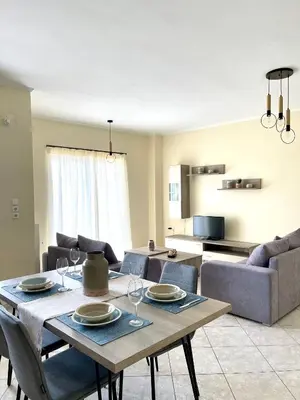 a living room with a table with wine glasses on it at Sky View Athens Airport Apartment in Spáta