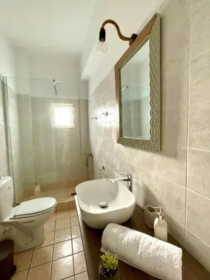 a bathroom with a sink and a toilet and a mirror at Sky View Athens Airport Apartment in Spáta