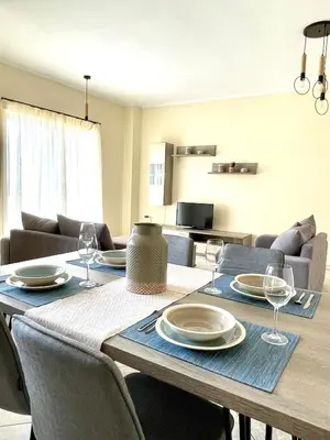 a dining room with a table with plates and wine glasses at Sky View Athens Airport Apartment in Spáta