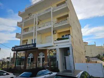 a tall building with cars parked in front of it at Sky View Athens Airport Apartment in Spáta