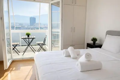 a white bedroom with a large white bed and a balcony at Athens View Studio Near Lycabettus Hill by MPS in Athens