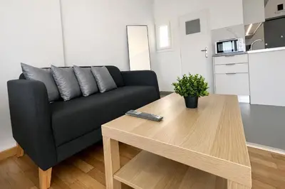 a living room with a black couch and a wooden table at Athens View Studio Near Lycabettus Hill by MPS in Athens