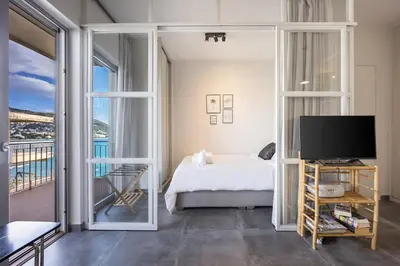 a bedroom with a bed and a tv and a balcony at Ioli Seafront Hideaway by Porto Rafti Marina in Porto Rafti