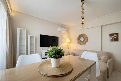 a living room with a table and chairs and a television at Like a Royal - Luxury Boho Apartment in Glyfada in Athens