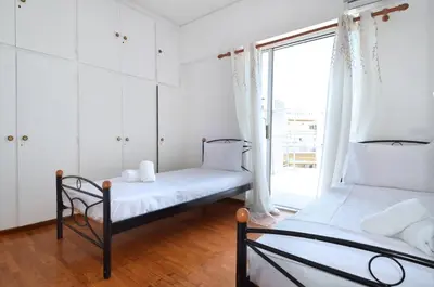 a bedroom with two beds and a window at A cute and comfortable two bedroom apartment in Piraeus