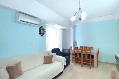 a living room with a white couch and a table at A cute and comfortable two bedroom apartment in Piraeus