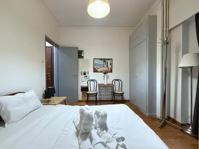 a bedroom with a white bed and a table and chairs at Charming and cozy studio apartment in Athens