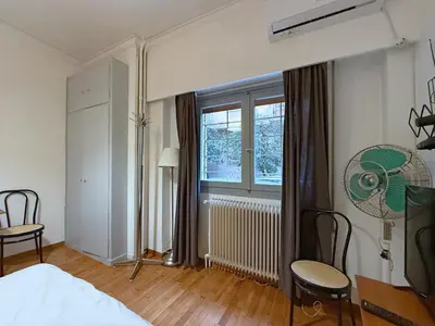 a bedroom with a bed and a window and chairs at Charming and cozy studio apartment in Athens