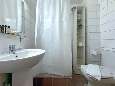 a white bathroom with a sink and a toilet at Charming and cozy studio apartment in Athens