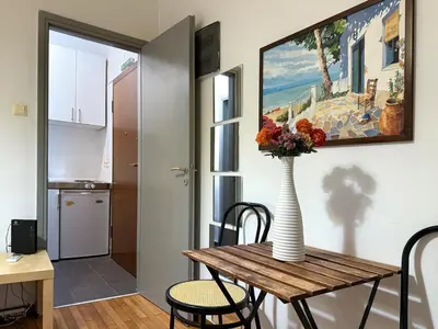 a vase of flowers on a wooden table in a room at Charming and cozy studio apartment in Athens