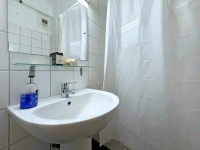 a white bathroom with a sink and a mirror at Charming and cozy studio apartment in Athens