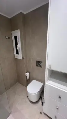 a bathroom with a white toilet and a sink at Beige House in Saronida