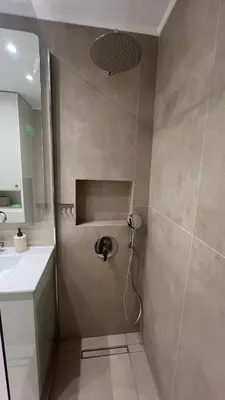 a shower with a faucet and a sink in a bathroom at Beige House in Saronida