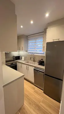 a kitchen with white cabinets and a black refrigerator at Beige House in Saronida