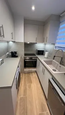 a kitchen with white cabinets and a wooden floor at Beige House in Saronida