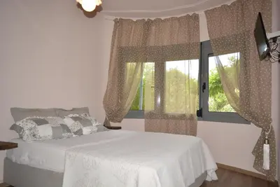 a bedroom with a white bed and a window at Varkiza's Cottages in Varkiza