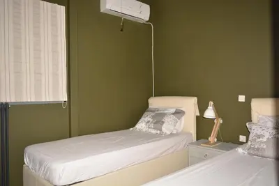 two beds in a room with green walls at Varkiza's Cottages in Varkiza