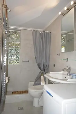 a white bathroom with a sink and a toilet at Varkiza's Cottages in Varkiza