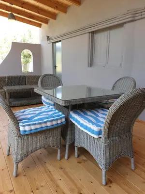 a dining room with wicker chairs and a table at Varkiza's Cottages in Varkiza