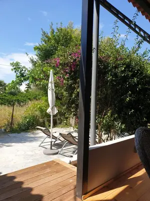 a patio with a umbrella and a chair and a umbrella and a table at Varkiza's Cottages in Varkiza