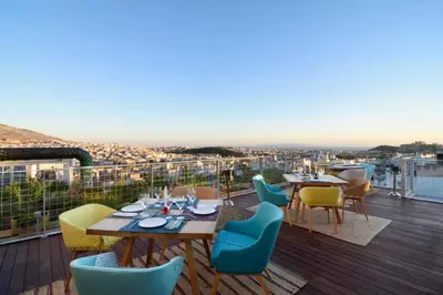 a restaurant with tables and chairs on a balcony at Coco-Mat Hotel Athens in Athens