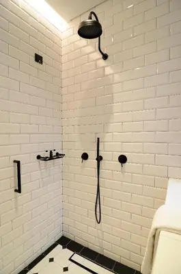 a white bathroom with a shower with a black and white floor at Coco-Mat Hotel Athens in Athens