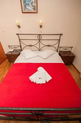 a bed with a red blanket with a robe on it at Cecil Hotel in Athens