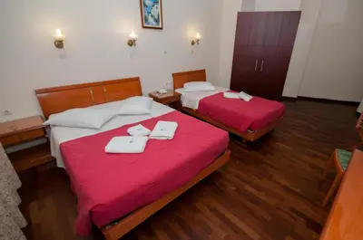 two beds in a room with red sheets and towels at Cecil Hotel in Athens