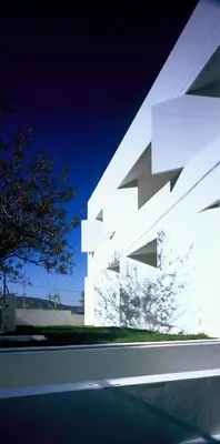 a white building with a tree in front of it at Infinity White Complex by GK Properties in Porto Rafti