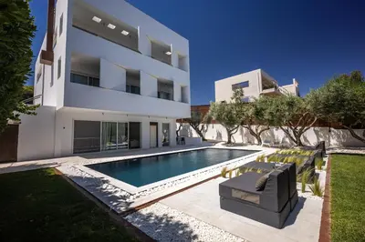 a swimming pool in front of a house at Infinity White Complex by GK Properties in Porto Rafti