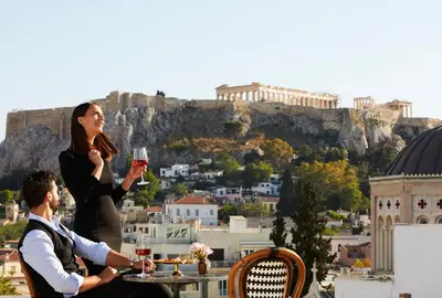 a man and a woman sitting at a table with wine glasses at Villa Brown Ermou, a member of Brown Hotels in Athens