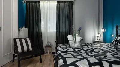 a bedroom with a black and white bed and a chair at Apartment at the foothills of Acropolis in Athens